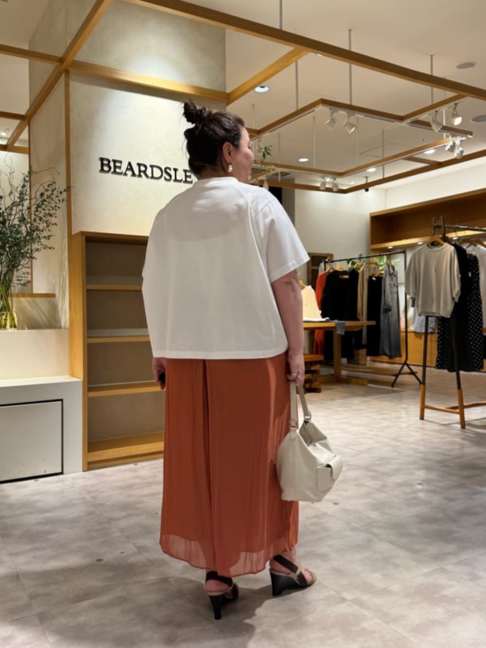 ホワイト系のトートバッグ、オレンジ系のその他パンツ、ホワイト系のTシャツ/カットソーを着用したレディースの春コーディネートの6枚目の写真