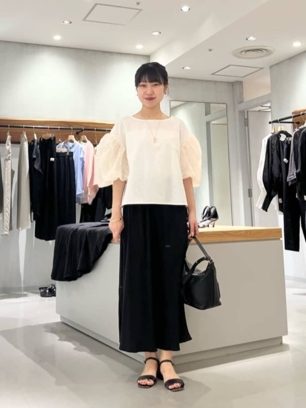 ブラック系のスカート、ホワイト系のシャツ/ブラウスを着用したレディースの夏コーディネートの2枚目の写真