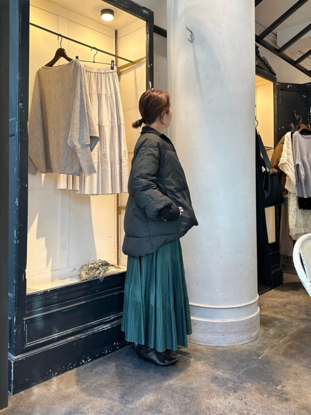 グリーン系のスカート、グレー系のニット/セーター、ブラック系のダウンジャケット/コートを着用したレディースの冬コーディネートの3枚目の写真