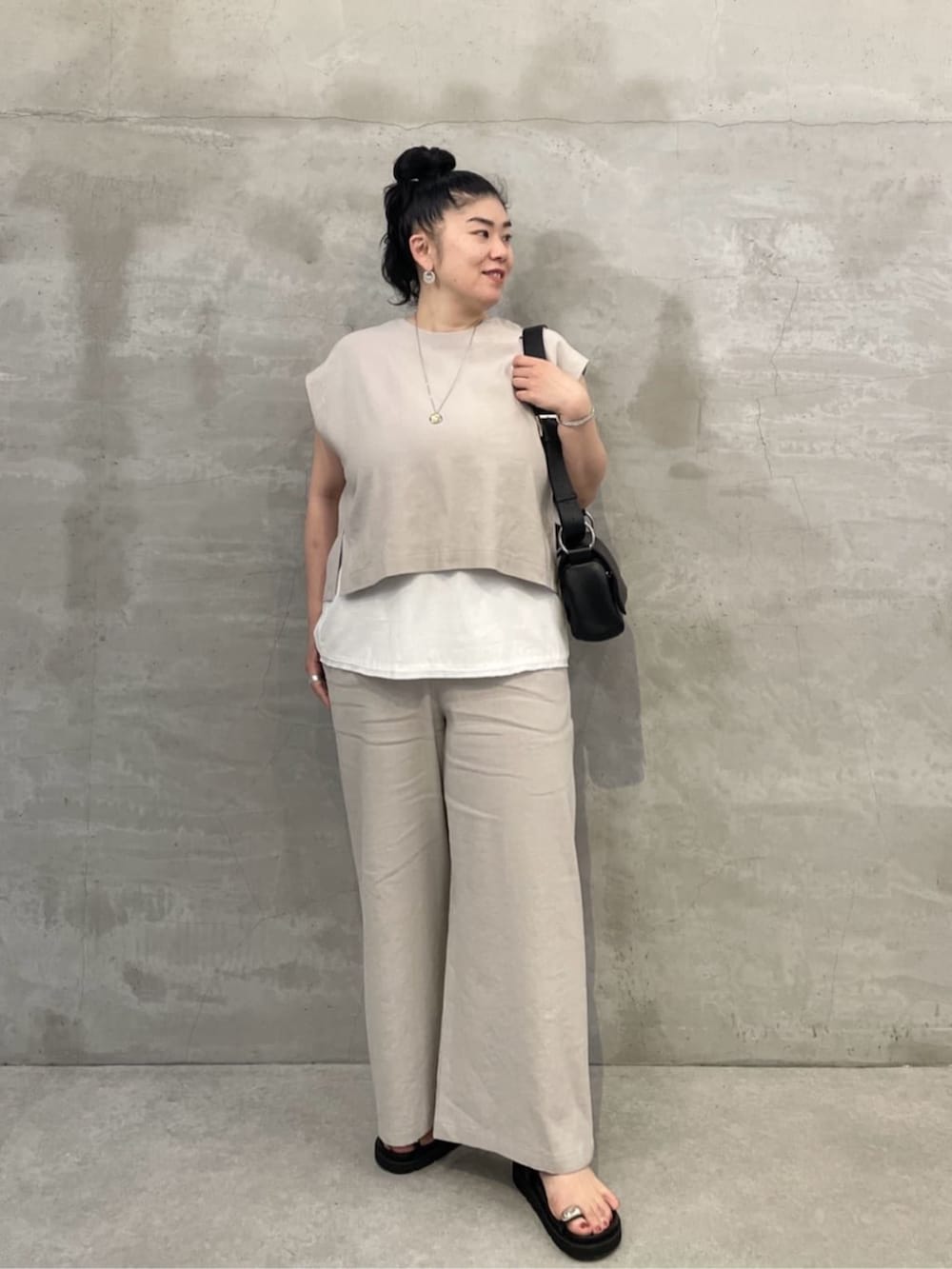 ホワイト系のタンクトップ、ブラック系のショルダーバッグ、ブラック系のサンダルを着用したレディースの春コーディネートの2枚目の写真