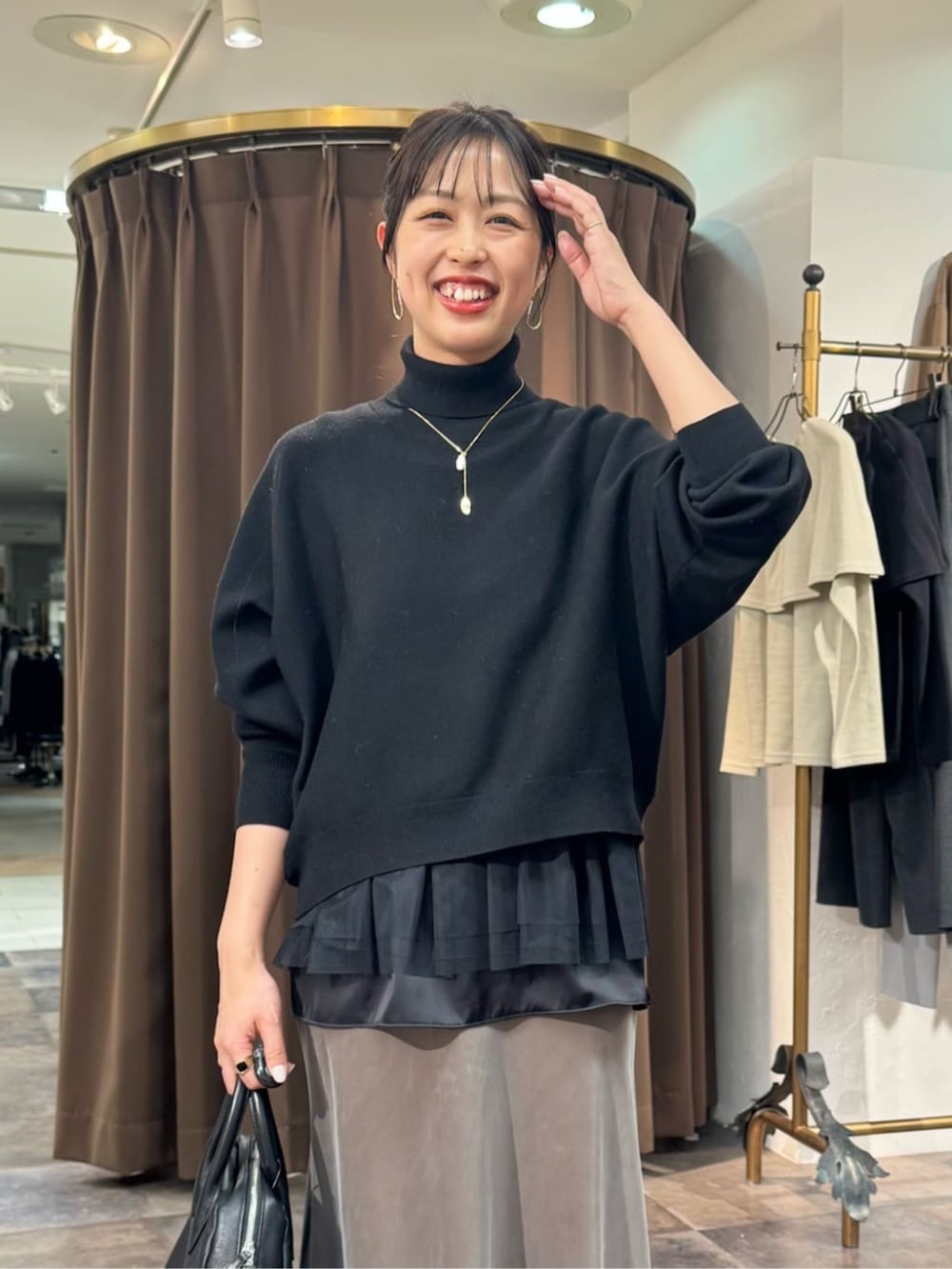 グリーン系のスカート、ブラック系のボストンバッグ、ブラック系のニット/セーターを着用したレディースの冬コーディネートの5枚目の写真