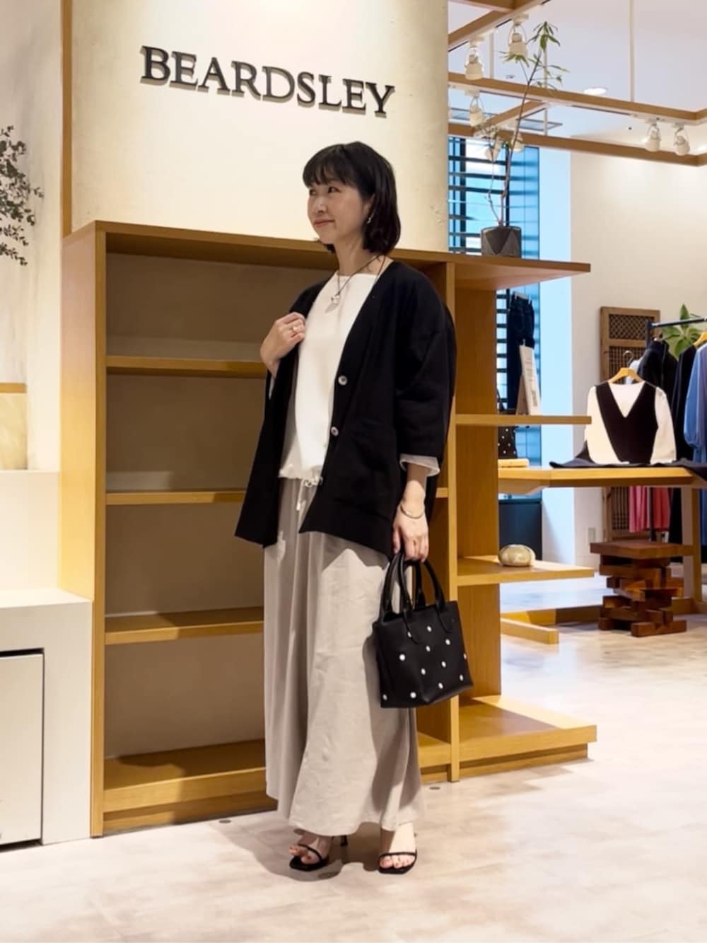 ブラック系のトートバッグ、ホワイト系のシャツ/ブラウス、グレー系のその他パンツを着用したレディースの春コーディネートの2枚目の写真