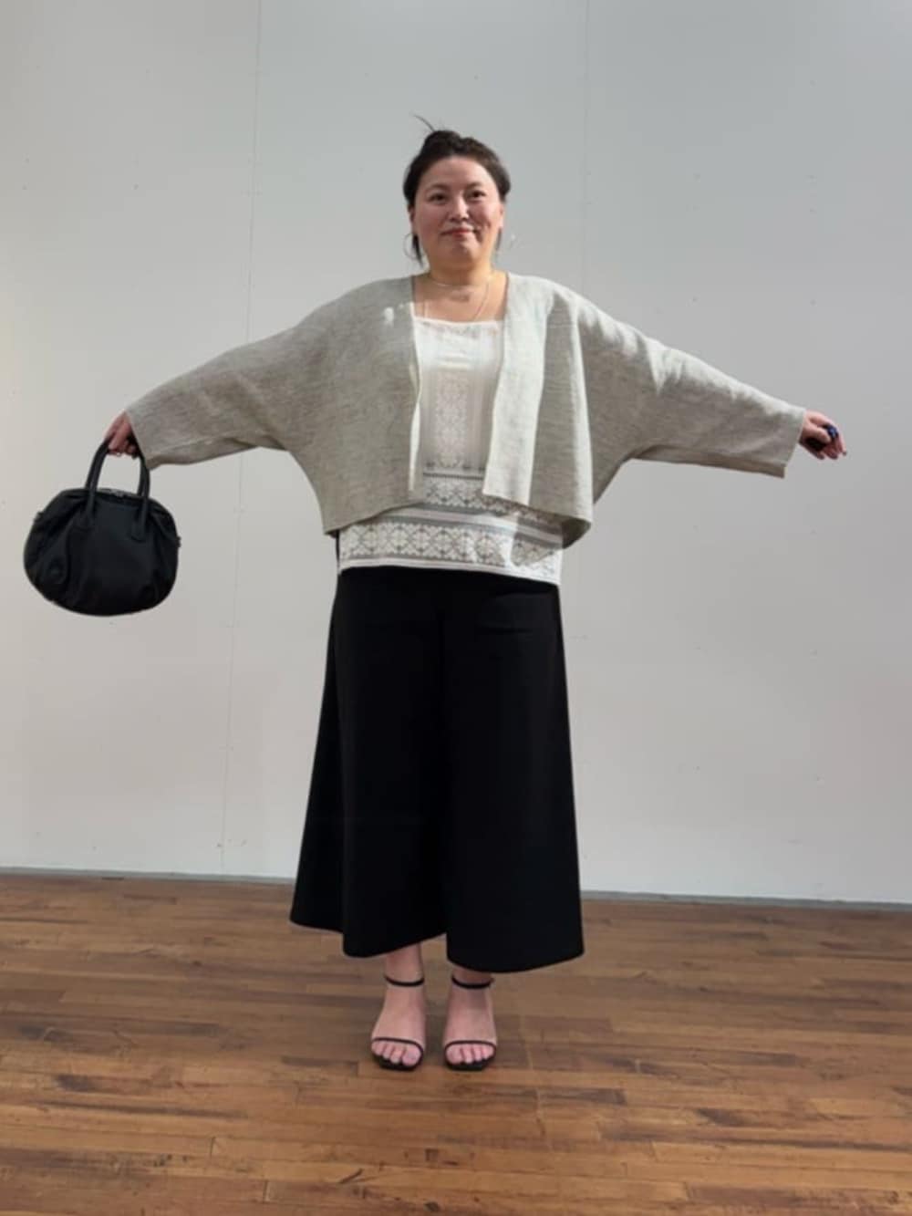 ブラック系のボストンバッグ、ホワイト系のシャツ/ブラウス、グレー系のカーディガン/ボレロを着用したレディースの春コーディネートの3枚目の写真