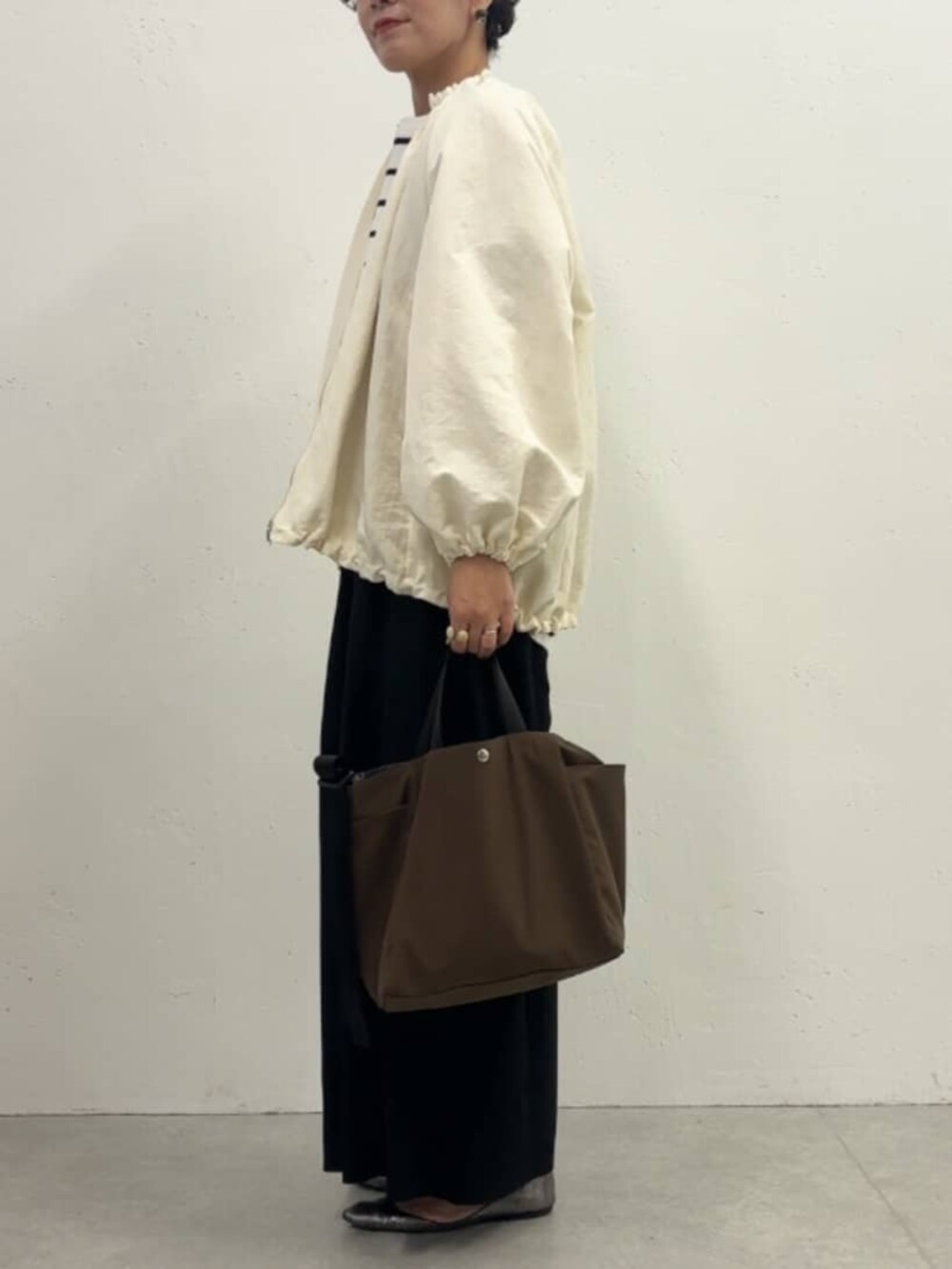 ホワイト系のノーカラージャケット、ブラック系のその他パンツ、ホワイト系のニット/セーターを着用したレディースの冬コーディネートの2枚目の写真