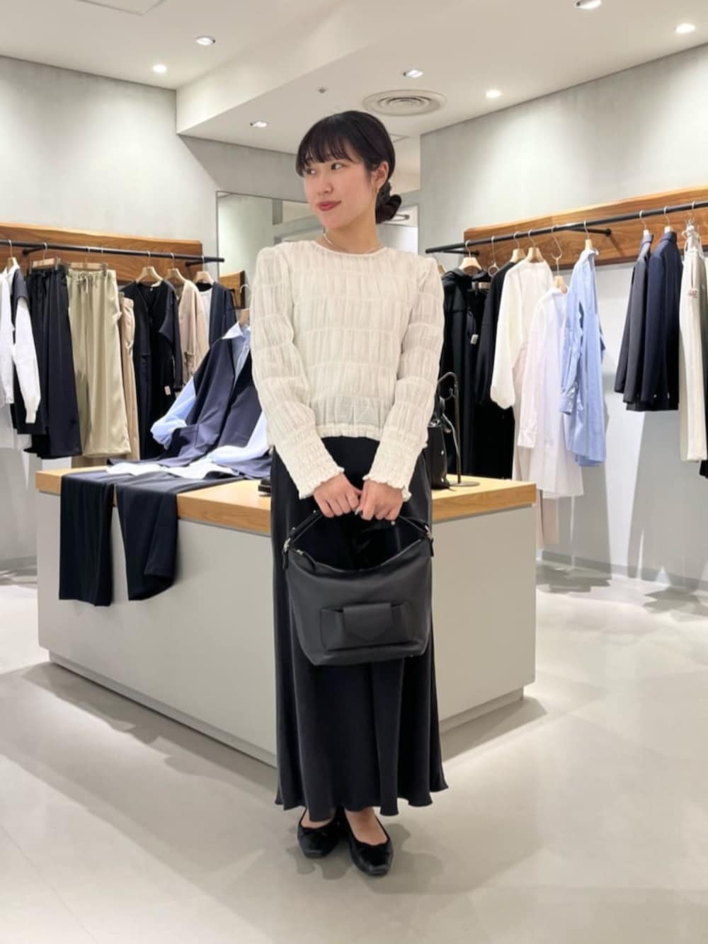 ブラック系のスカート、ブラック系のトートバッグ、ホワイト系のシャツ/ブラウスを着用したレディースの春コーディネートの2枚目の写真