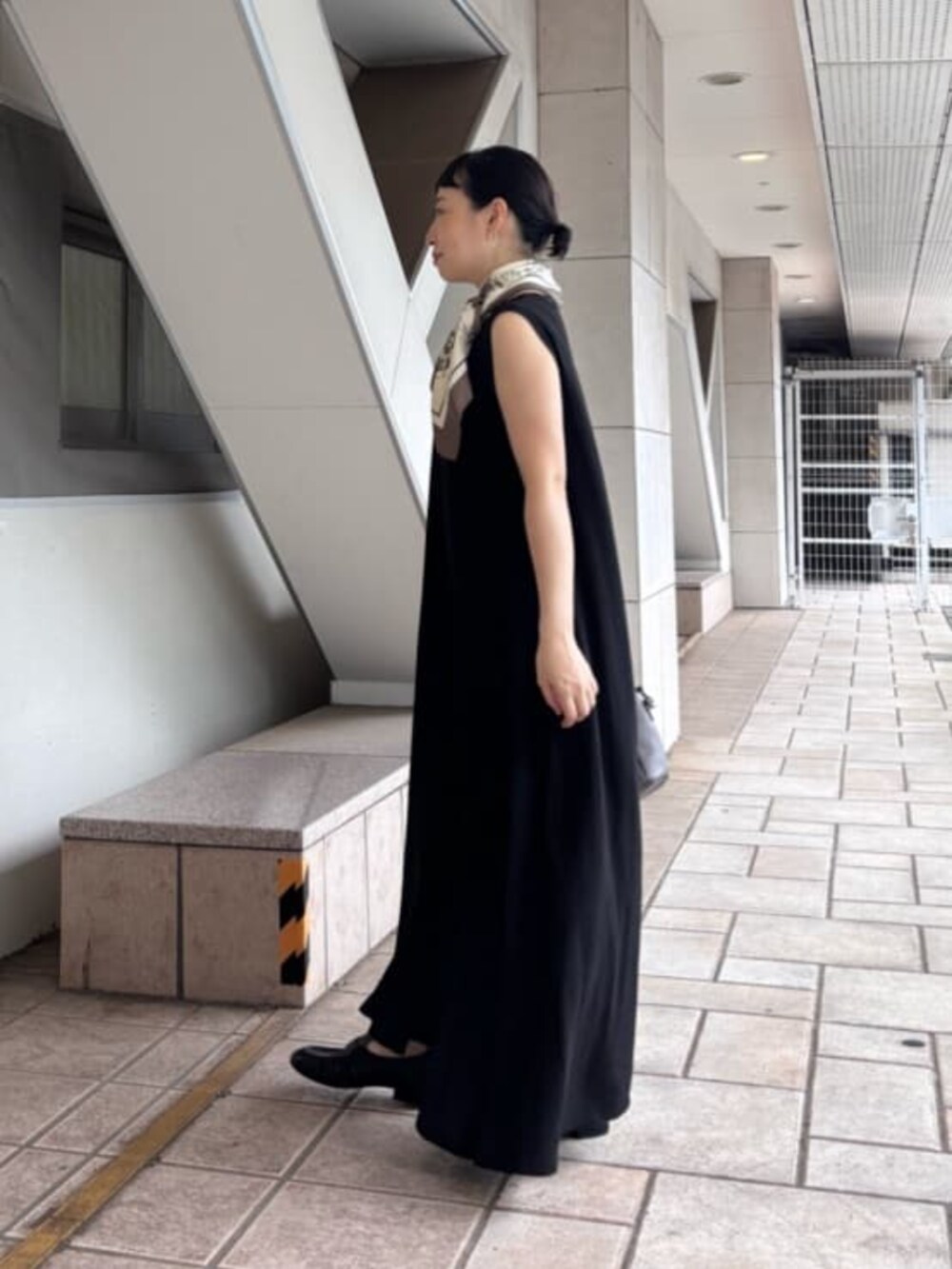 グレー系のハンドバッグ、ブラック系のサンダル、ブラック系のワンピースを着用したレディースの夏コーディネートの4枚目の写真