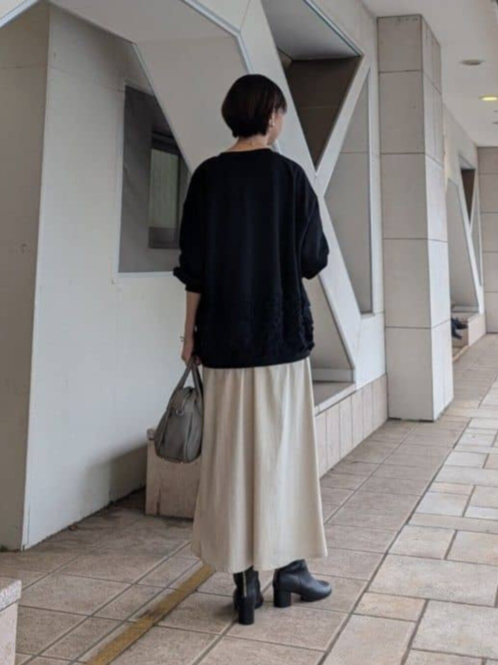 ベージュ系のスカート、ブラック系のTシャツ/カットソー、グレー系のトートバッグを着用したレディースの秋コーディネートの3枚目の写真