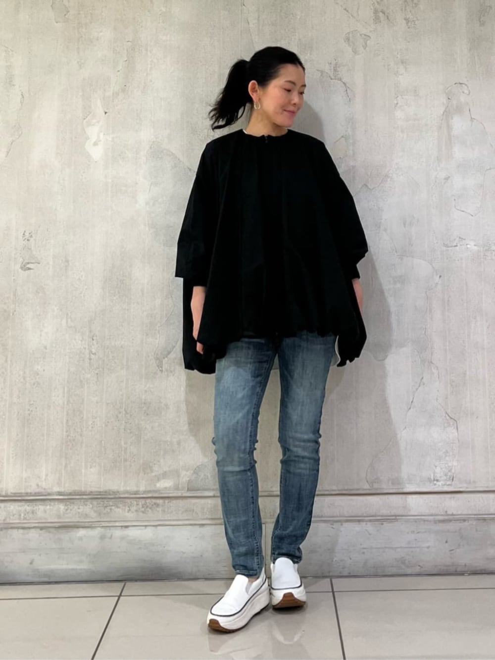 ホワイト系のスニーカー、ブルー系のデニムパンツ、ブラック系のボストンバッグを着用したレディースの冬コーディネートの7枚目の写真