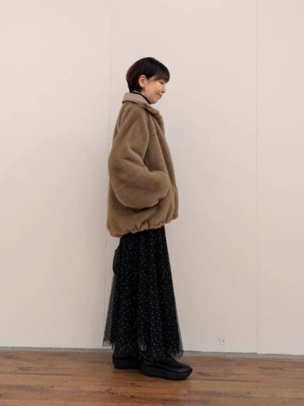ブラック系のスカート、ベージュ系のブルゾンを着用したレディースの秋コーディネートの3枚目の写真