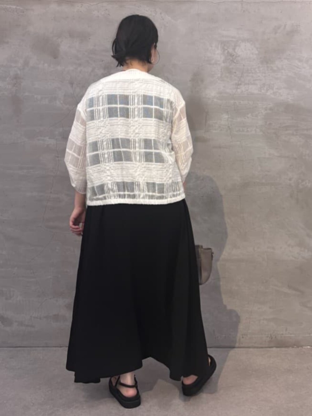 グレー系のハンドバッグ、ブラック系のワンピース、ホワイト系のブルゾンを着用したレディースの夏コーディネートの5枚目の写真