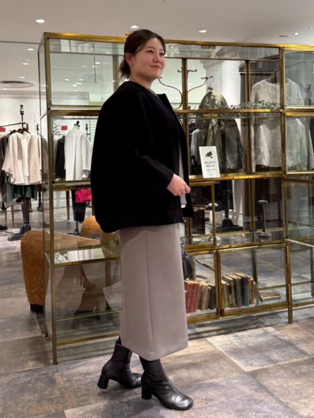 ブラウン系のスカート、ブラック系のノーカラーコートを着用したレディースの冬コーディネートの2枚目の写真