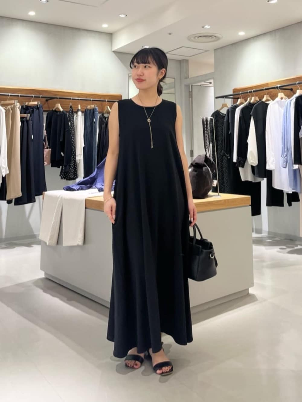 ブラック系のハンドバッグ、ブラック系のワンピースを着用したレディースの春コーディネートの2枚目の写真