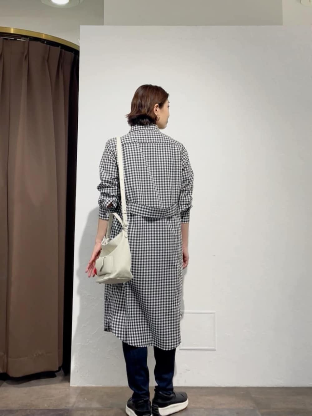 ブルー系のデニムパンツ、ブラック系のワンピース、ホワイト系のトートバッグを着用したレディースの春コーディネートの4枚目の写真