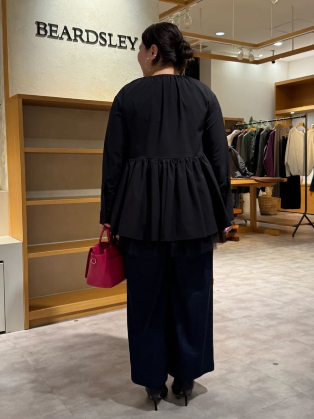 ピンク系のハンドバッグ、ブラック系のブーツ、ブラック系のブルゾンを着用したレディースの冬コーディネートの4枚目の写真