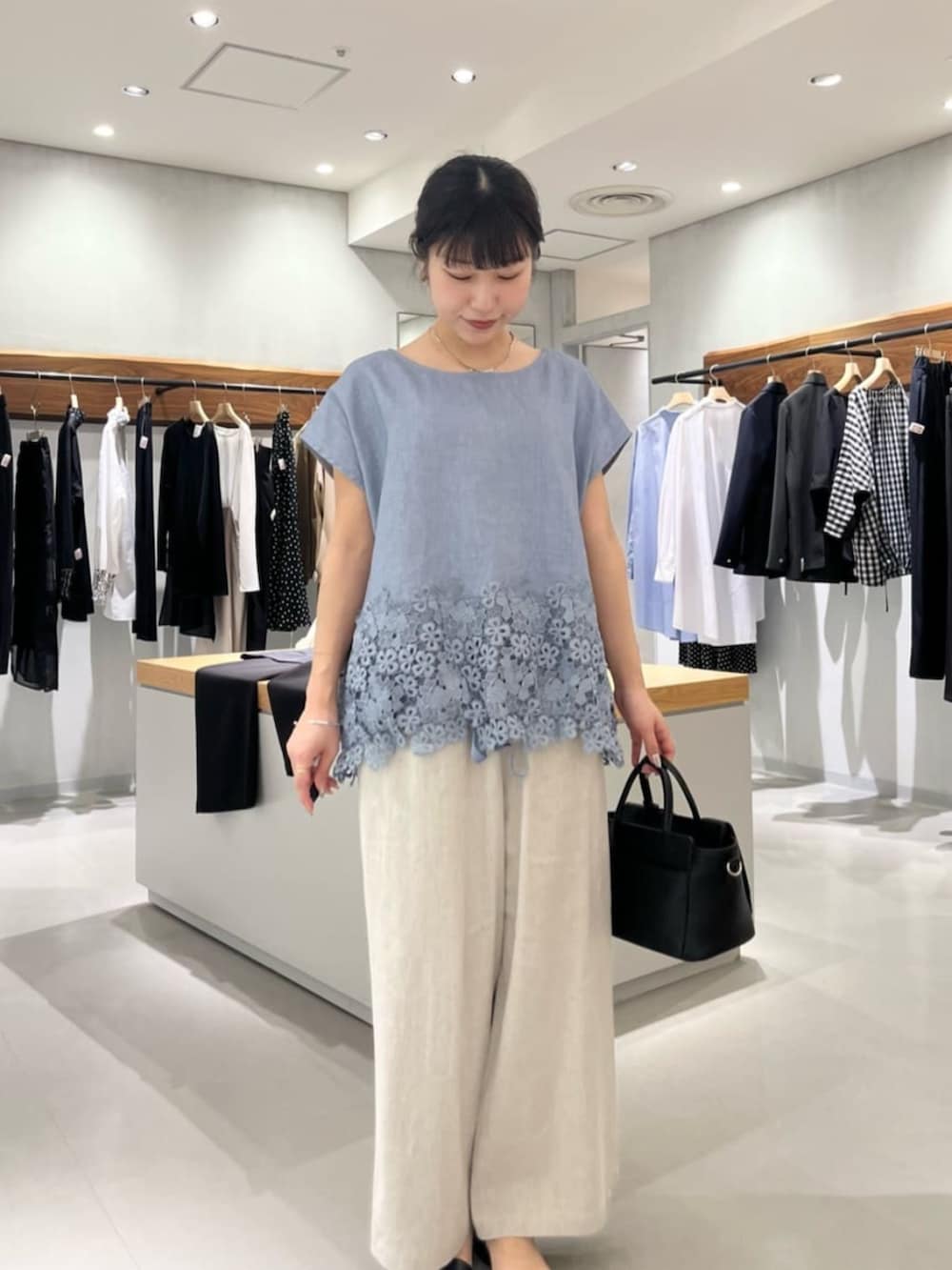 ブラック系のハンドバッグ、ベージュ系のその他パンツ、ブルー系のシャツ/ブラウスを着用したレディースの夏コーディネートの4枚目の写真