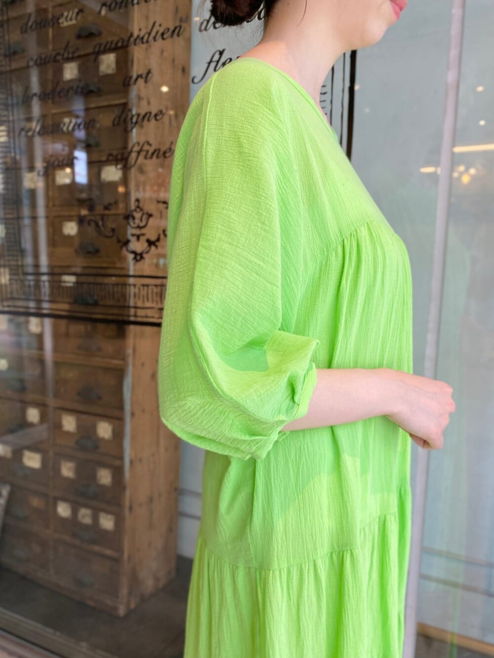 グリーン系のワンピース、ホワイト系のかごバッグ、ブラウン系のサンダルを着用したレディースの夏コーディネートの3枚目の写真