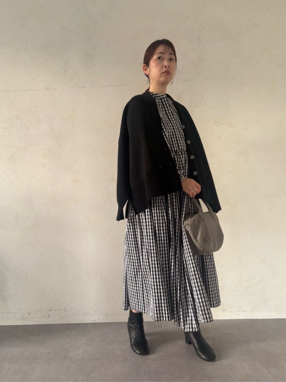 グレー系のボストンバッグ、ブラック系のカーディガン/ボレロ、ブラック系のワンピースを着用したレディースの冬コーディネートの2枚目の写真