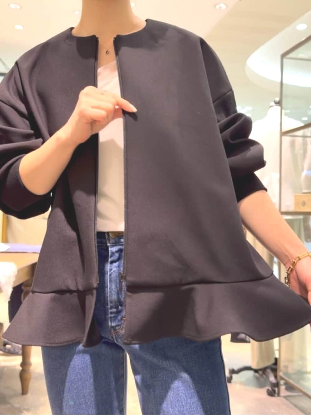 ブラック系のトートバッグ、ブラック系のブルゾン、ブルー系のデニムパンツを着用したレディースの夏コーディネートの3枚目の写真