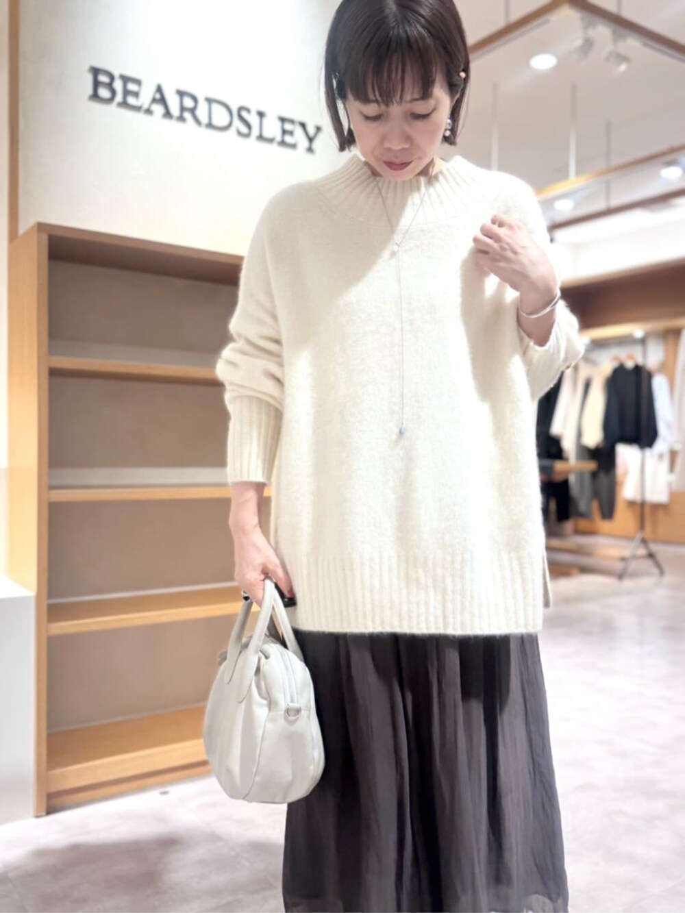 グレー系のボストンバッグ、ホワイト系のニット/セーター、ブラウン系のその他パンツを着用したレディースの冬コーディネートの5枚目の写真