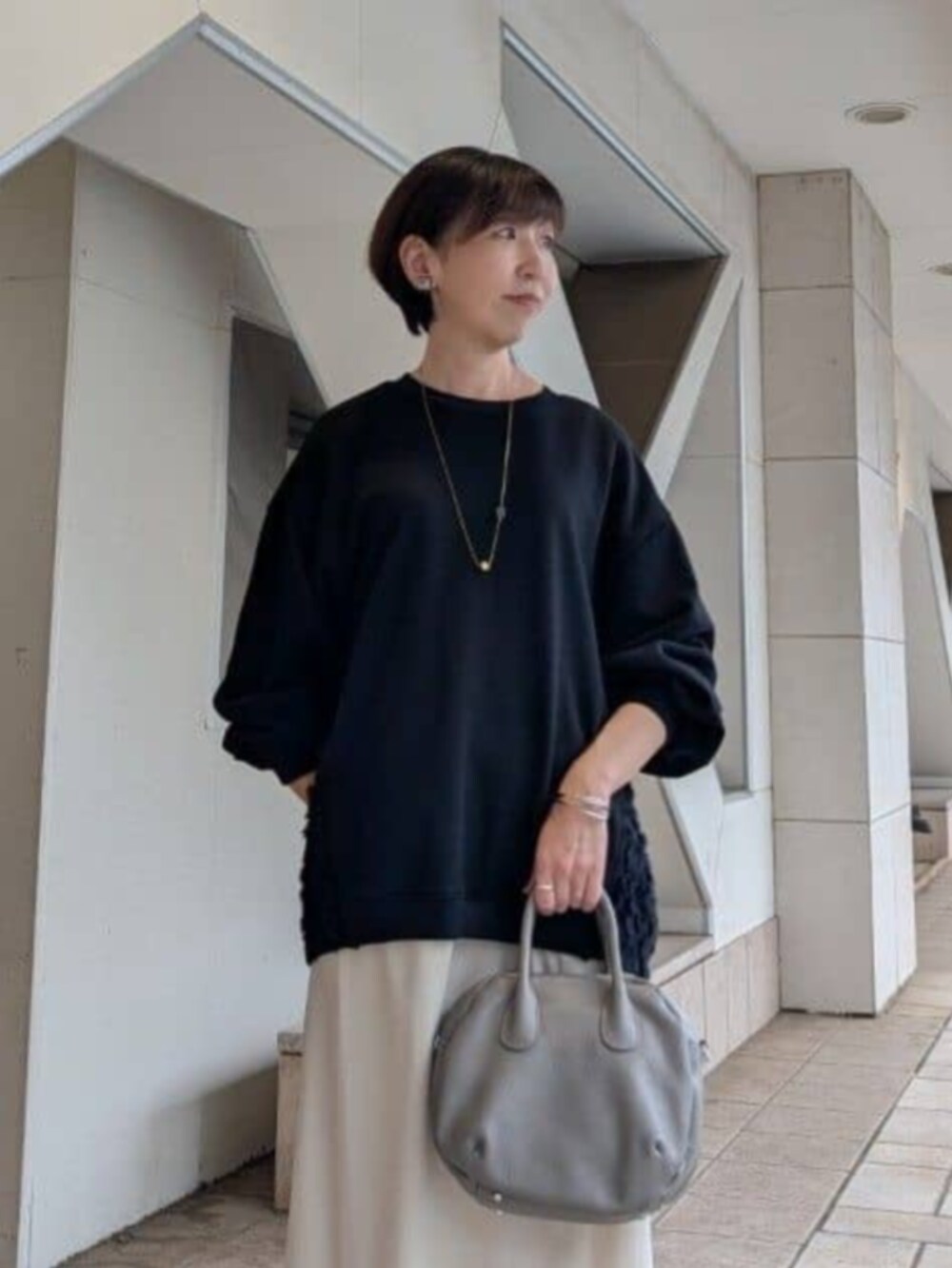 ベージュ系のスカート、ブラック系のTシャツ/カットソー、グレー系のトートバッグを着用したレディースの秋コーディネートの7枚目の写真