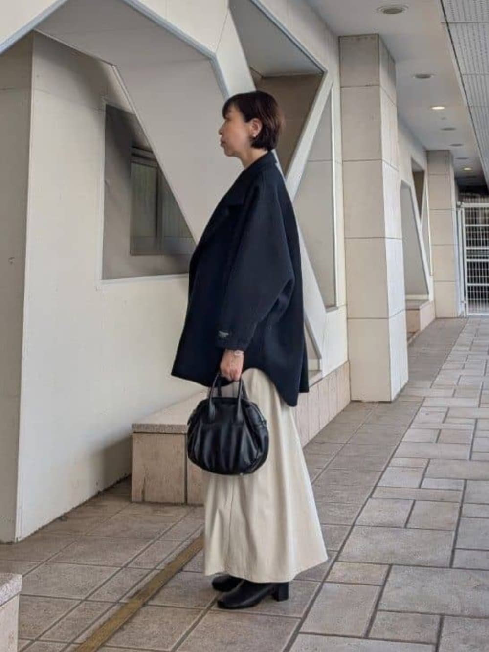 ブラック系のトートバッグ、ブラック系のその他アウター、ベージュ系のスカートを着用したレディースの夏コーディネートの2枚目の写真