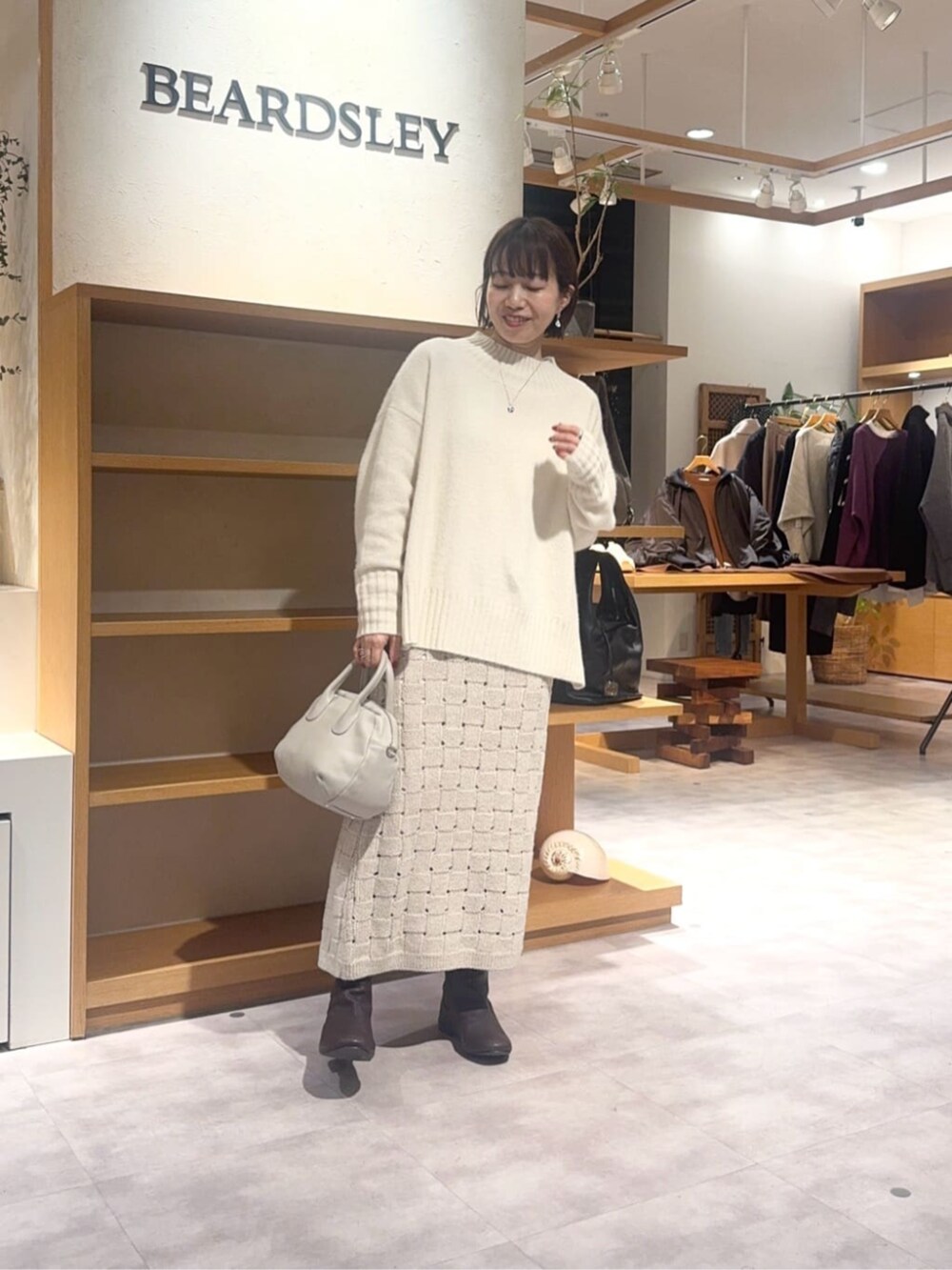 グレー系のボストンバッグ、ベージュ系のスカート、ブラウン系のダウンジャケット/コートを着用したレディースの冬コーディネートの6枚目の写真