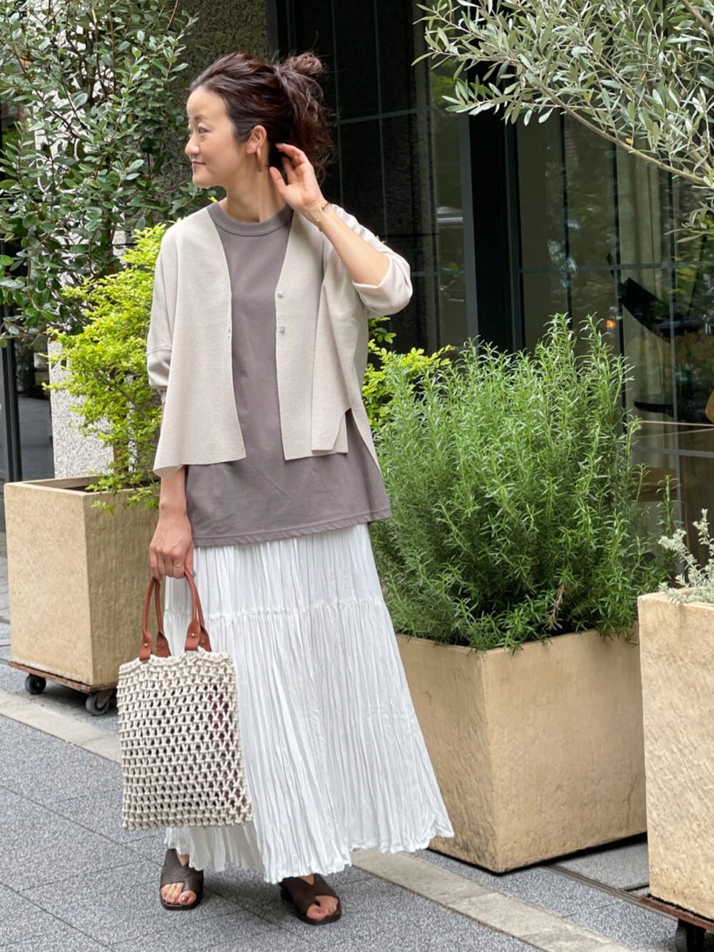 ベージュ系のカーディガン/ボレロ、ブラウン系のTシャツ/カットソー、ホワイト系のスカートを着用したレディースの春コーディネートの2枚目の写真