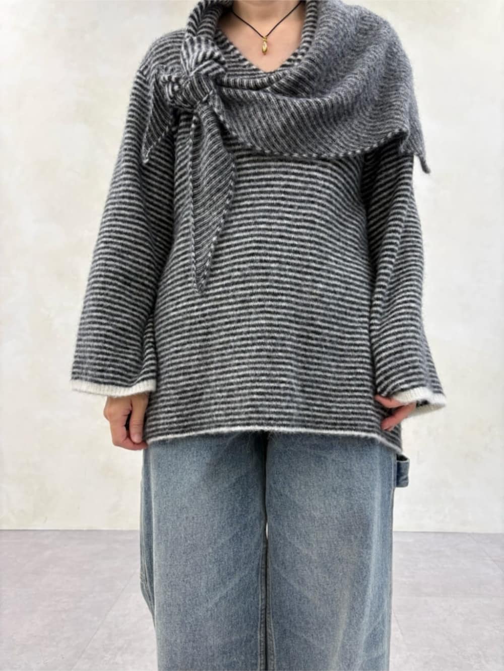 ブルー系のデニムパンツ、ブラック系のブーツ、ブラック系のニット/セーターを着用したレディースの秋コーディネートの3枚目の写真