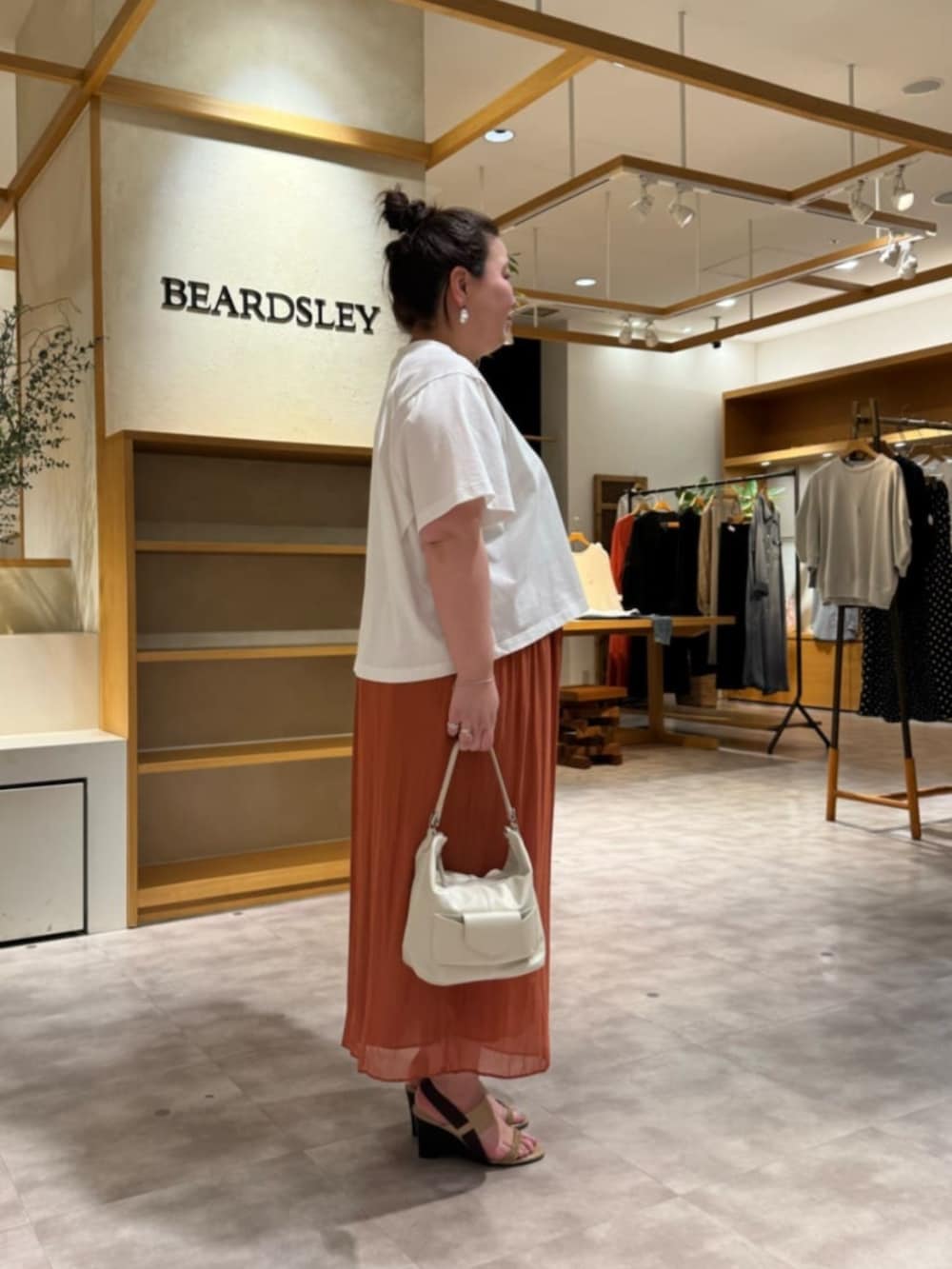 ホワイト系のトートバッグ、オレンジ系のその他パンツ、ホワイト系のTシャツ/カットソーを着用したレディースの春コーディネートの3枚目の写真