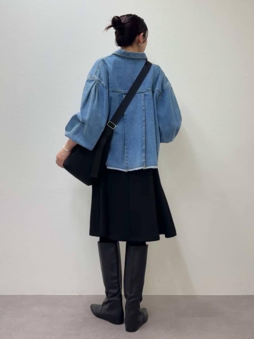 ブルー系のデニムジャケット、ブラック系のワンピース、ブラック系のトートバッグを着用したレディースの冬コーディネートの5枚目の写真