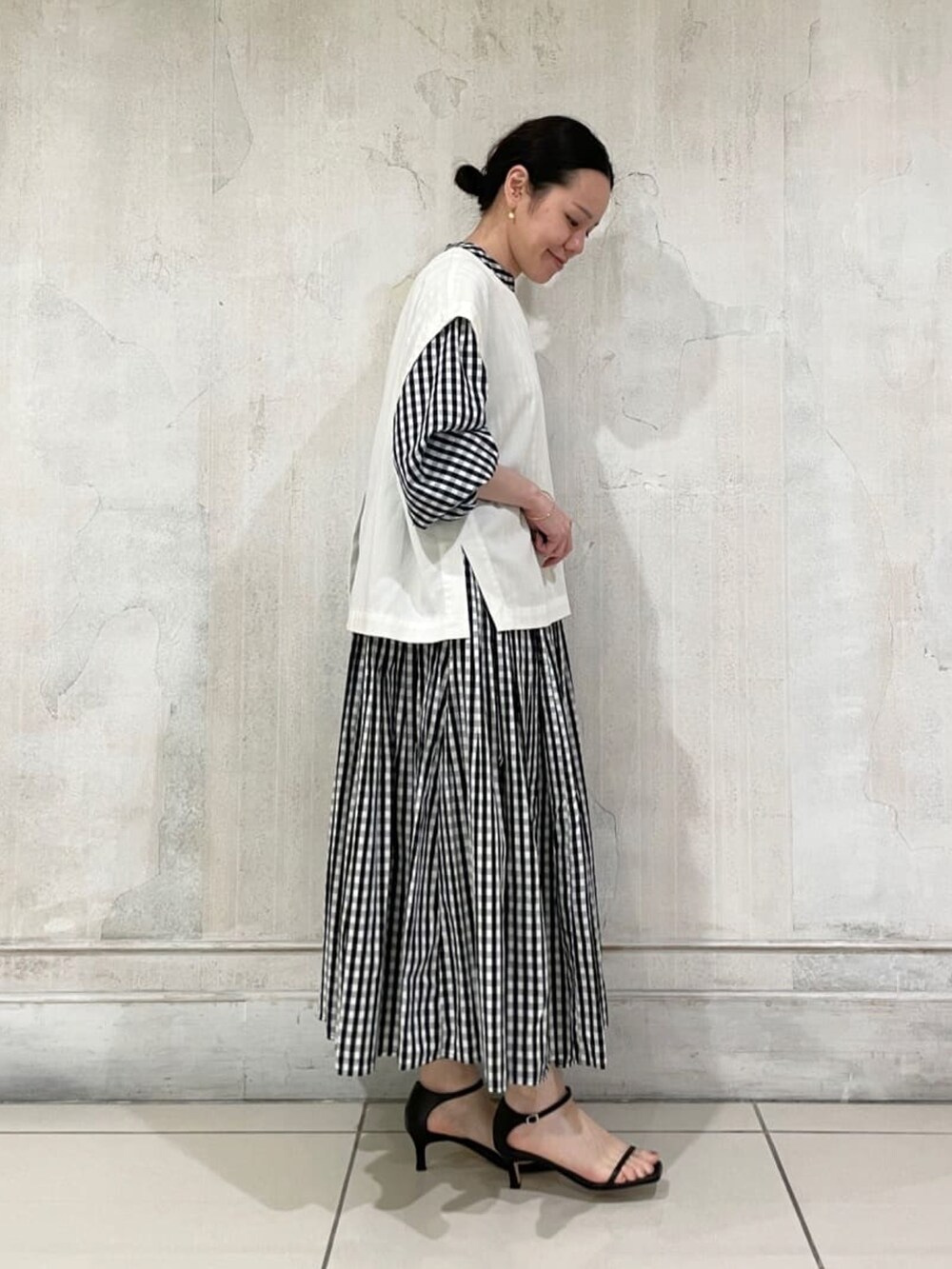 ホワイト系のベスト、ブラック系のワンピースを着用したレディースの夏コーディネートの3枚目の写真