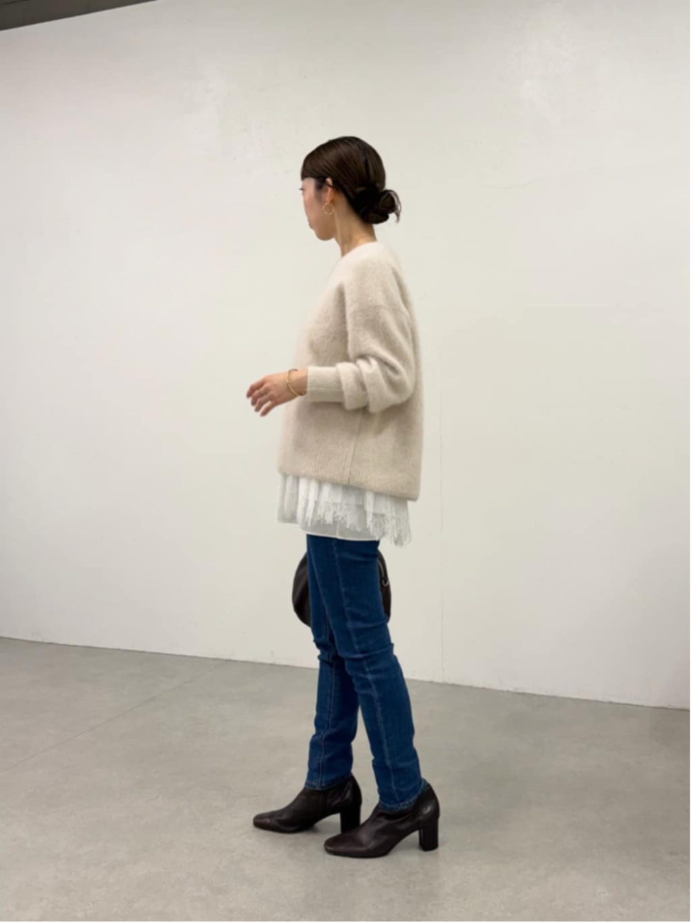 ブルー系のデニムパンツ、ホワイト系のタンクトップ、ホワイト系のニット/セーターを着用したレディースの秋コーディネートの2枚目の写真