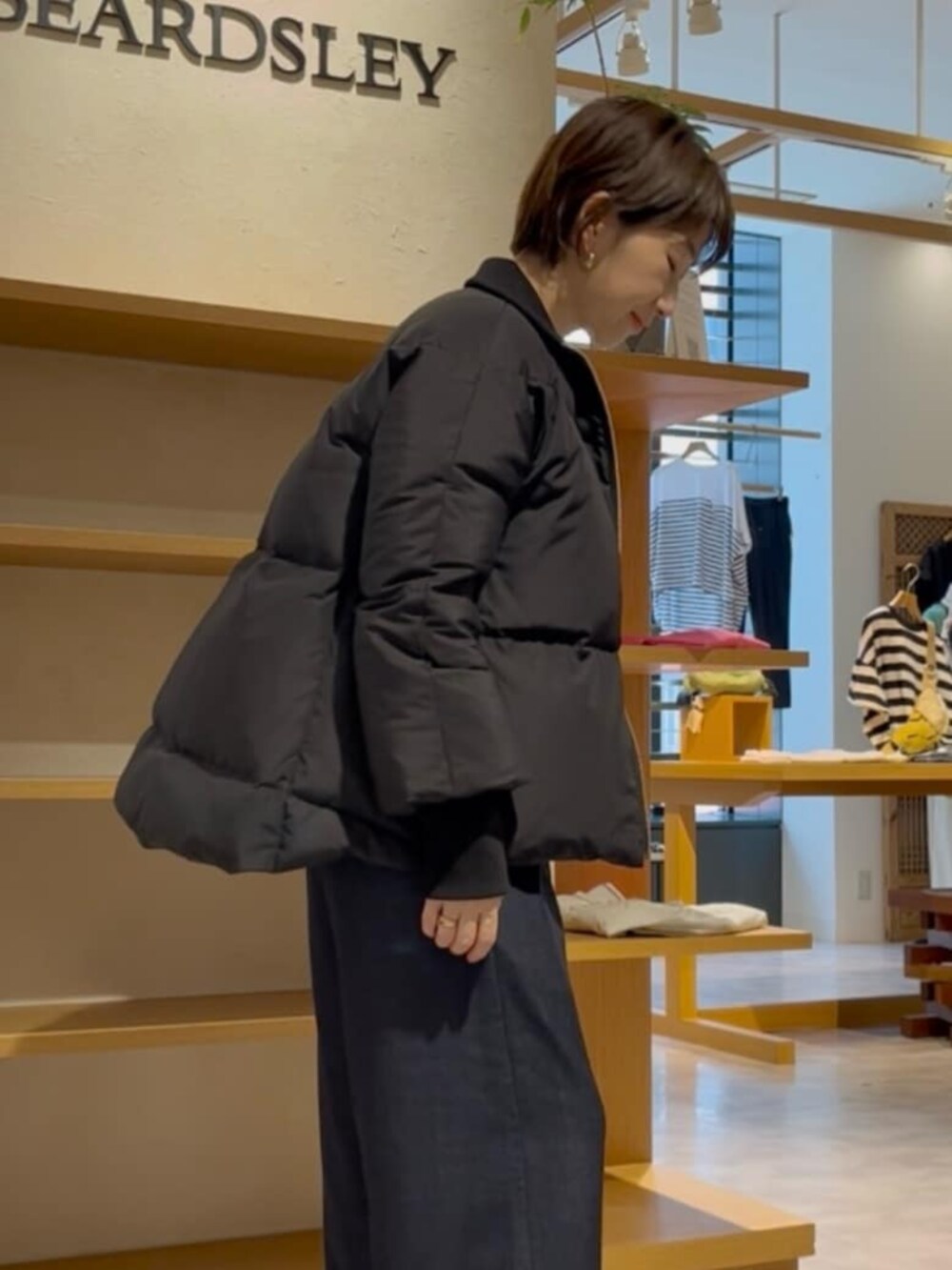 ブルー系のその他パンツ、グレー系のニット/セーター、ブラック系のダウンジャケット/コートを着用したレディースの冬コーディネートの5枚目の写真