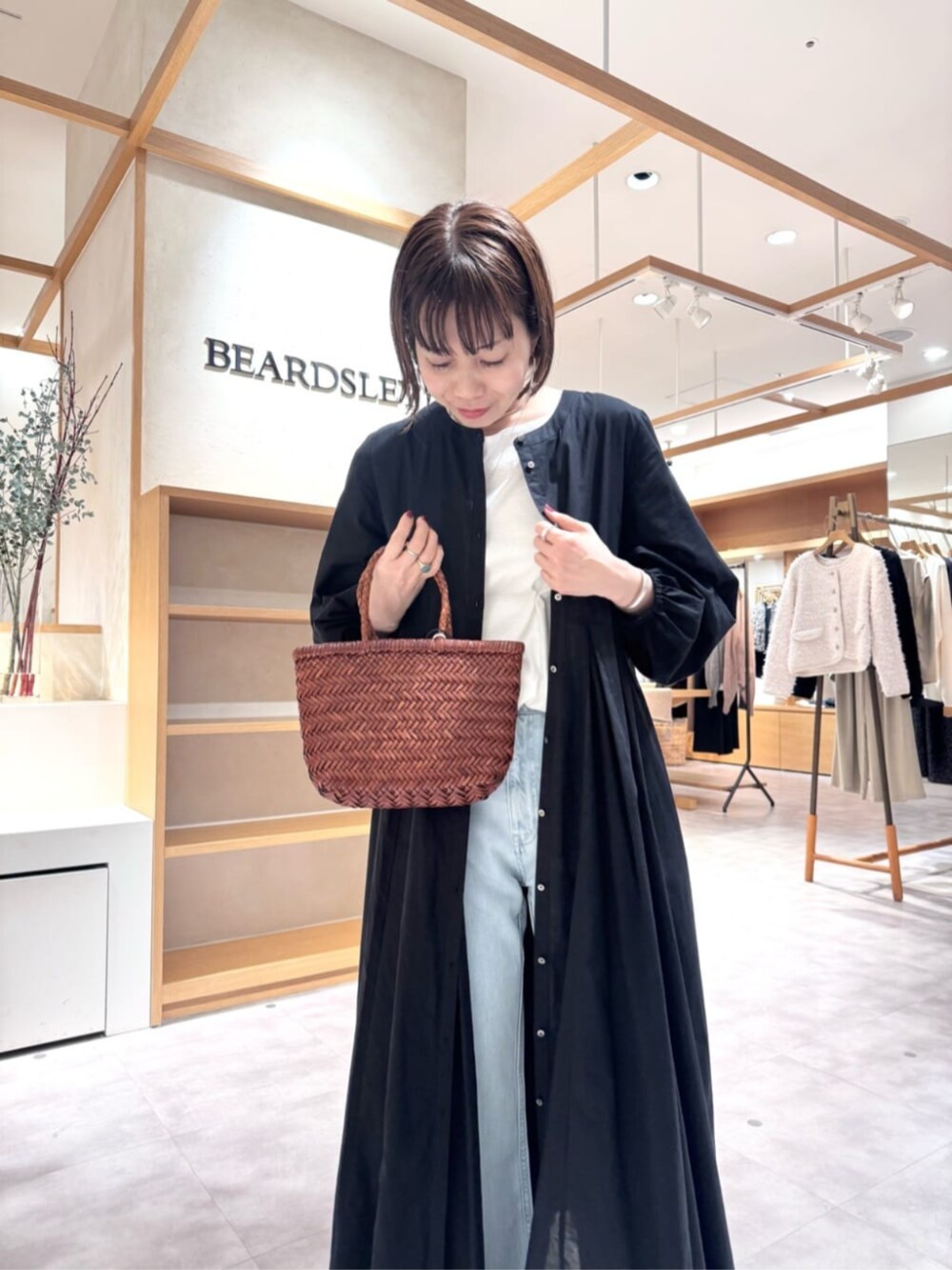 ブルー系のデニムパンツ、イエロー系のトートバッグ、ブラック系のワンピースを着用したレディースの冬コーディネートの5枚目の写真