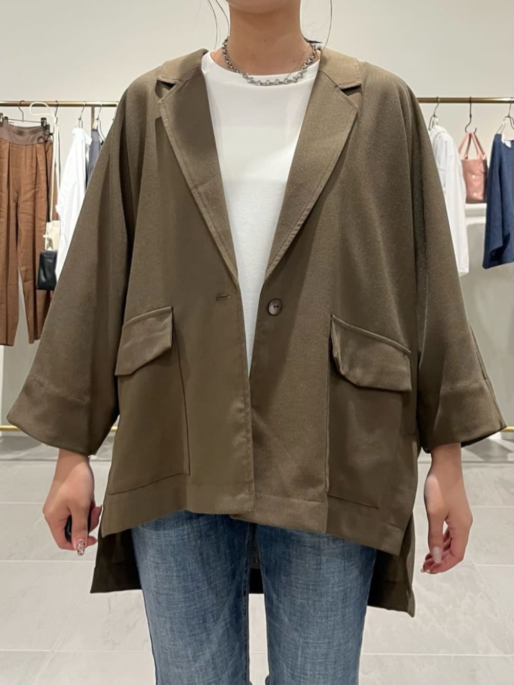 ブルー系のデニムパンツ、ブラック系のショルダーバッグ、ブラウン系のテーラードジャケットを着用したレディースの春コーディネートの4枚目の写真