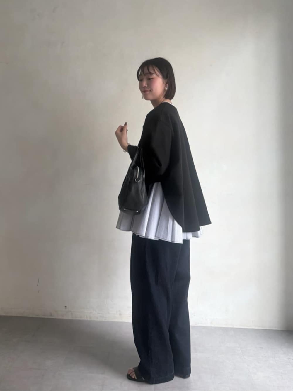 ブラック系のボストンバッグ、ブラック系のTシャツ/カットソー、ブルー系のデニムパンツを着用したレディースの冬コーディネートの4枚目の写真