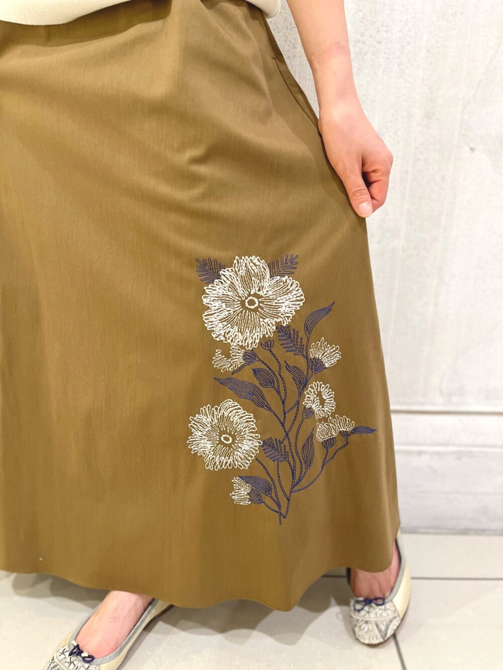 イエロー系のスカート、ホワイト系のニット/セーター、ベージュ系のバレエシューズを着用したレディースの冬コーディネートの5枚目の写真