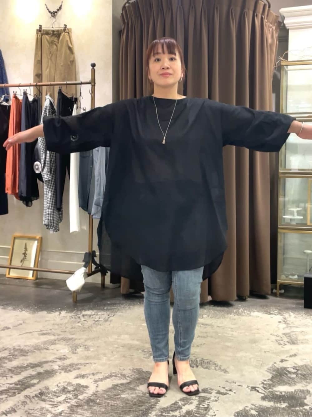 ブルー系のデニムパンツ、ホワイト系のショルダーバッグ、ブラック系のシャツ/ブラウスを着用したレディースの春コーディネートの6枚目の写真