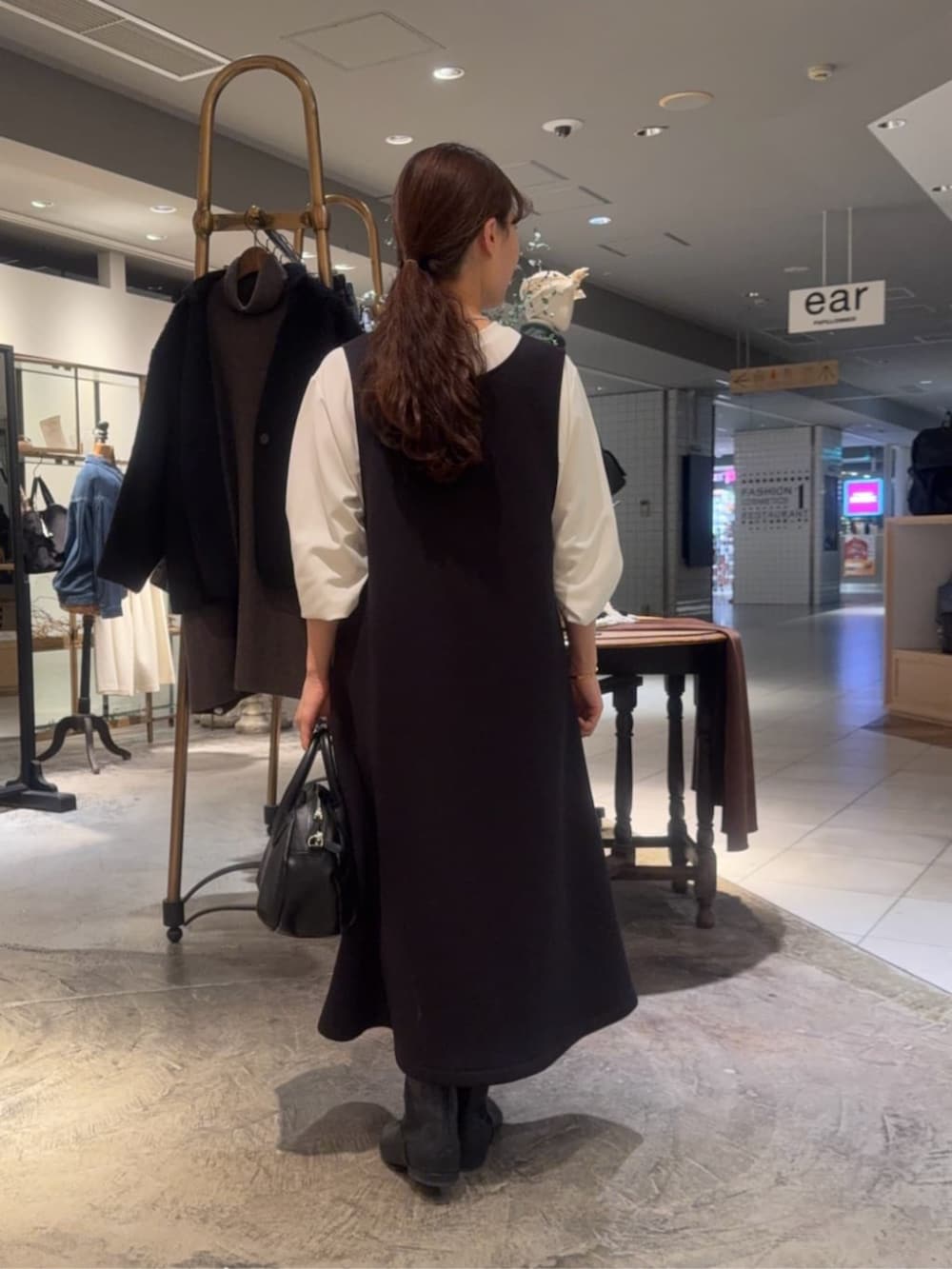 ホワイト系のシャツ/ブラウス、ブラック系のブーツ、ブラック系のジャンパースカートを着用したレディースの冬コーディネートの2枚目の写真