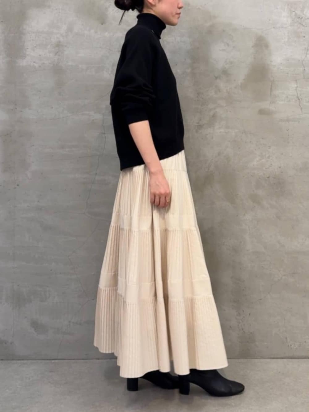 ホワイト系のスカート、ブラック系のボストンバッグ、ブラック系のニット/セーターを着用したレディースの冬コーディネートの4枚目の写真