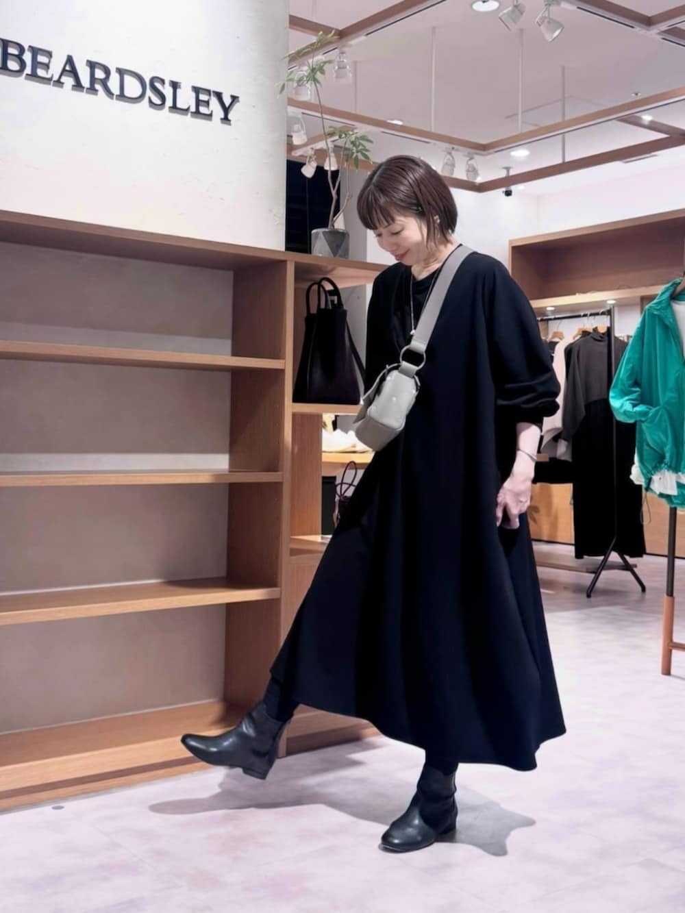 ブラック系のブーツ、ブラック系のワンピース、グレー系のショルダーバッグを着用したレディースの冬コーディネートの2枚目の写真