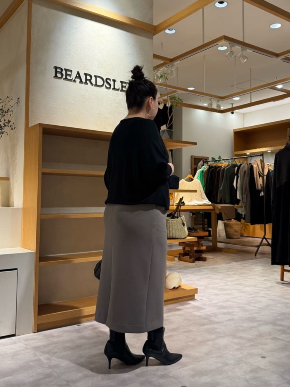 ブラック系のニット/セーター、ブラック系のブーツ、ブラウン系のスカートを着用したレディースの冬コーディネートの5枚目の写真