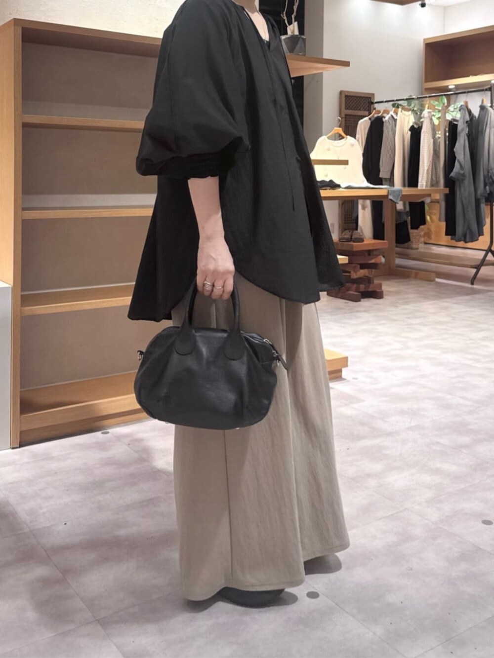 ブラック系のボストンバッグ、ベージュ系のその他パンツ、ブラック系のシャツ/ブラウスを着用したレディースの春コーディネートの6枚目の写真
