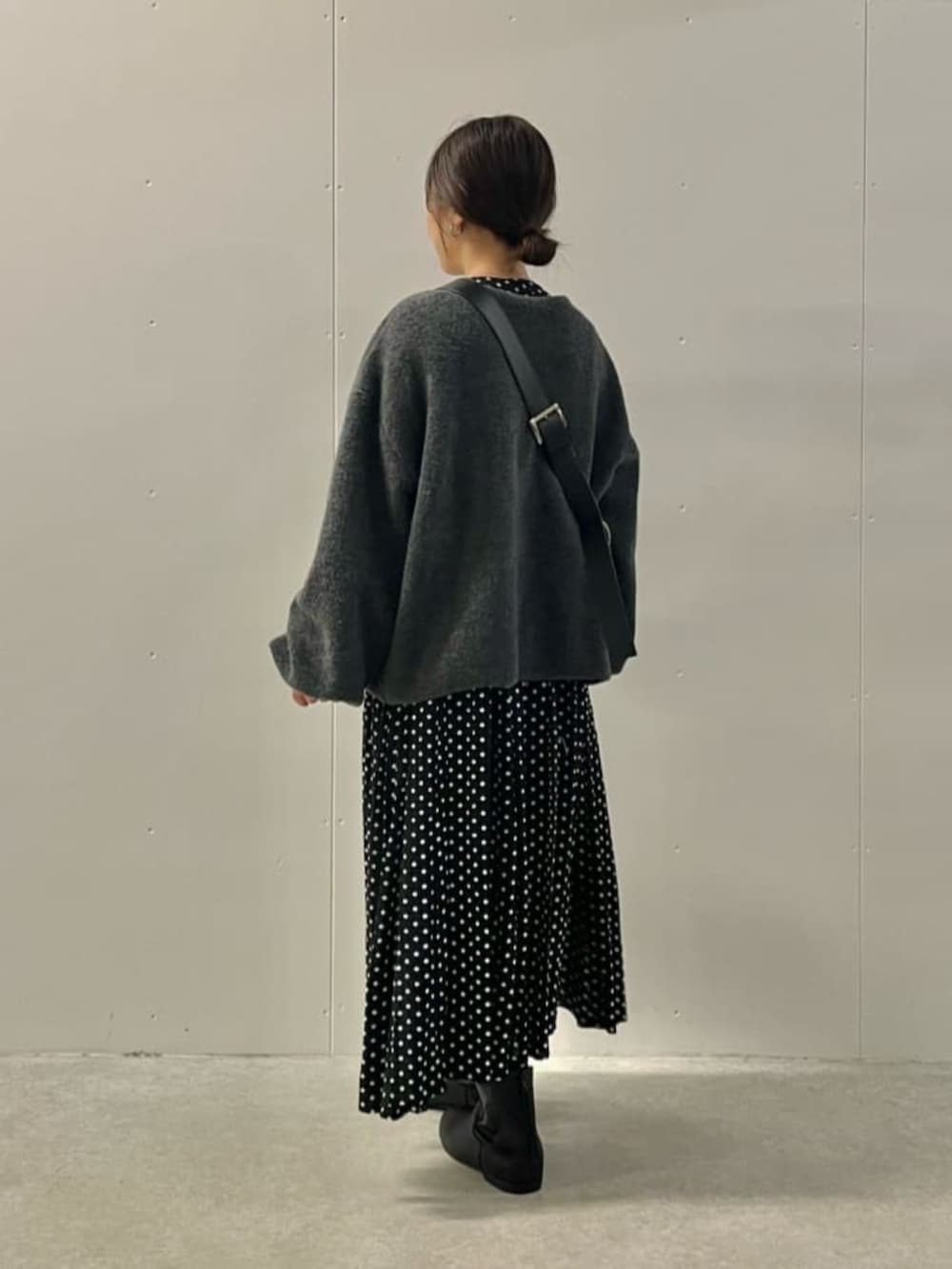 ブラック系のワンピース、ブラック系のブーツ、グレー系のニット/セーターを着用したレディースの冬コーディネートの5枚目の写真