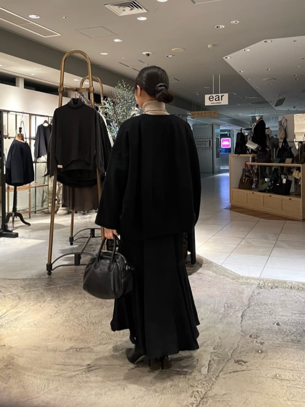 ブラック系のボストンバッグ、ブラック系のノーカラーコートを着用したレディースの冬コーディネートの4枚目の写真