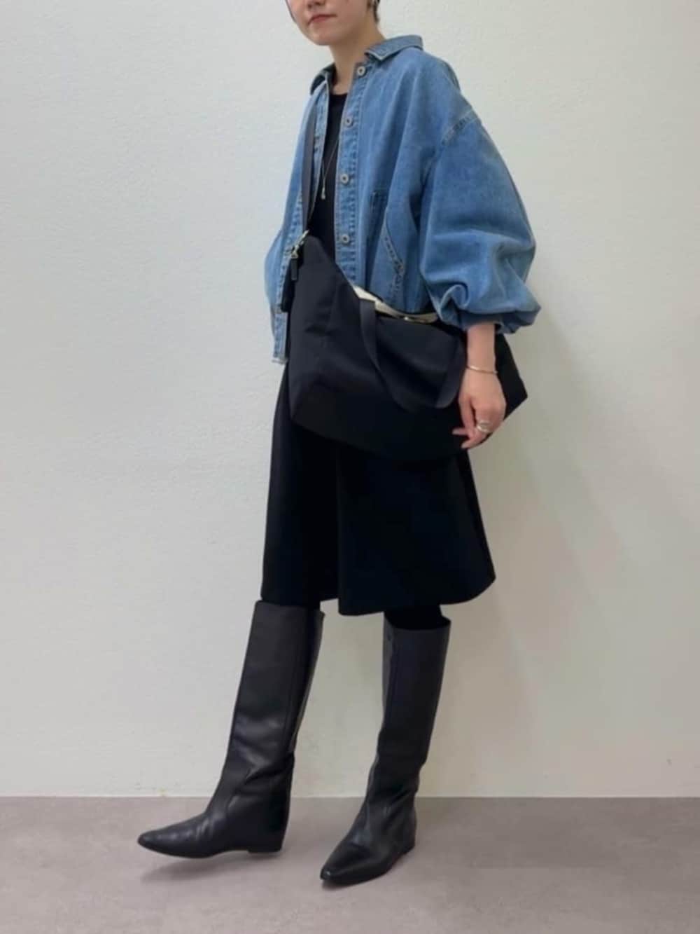 ブルー系のデニムジャケット、ブラック系のワンピース、ブラック系のトートバッグを着用したレディースの冬コーディネートの3枚目の写真