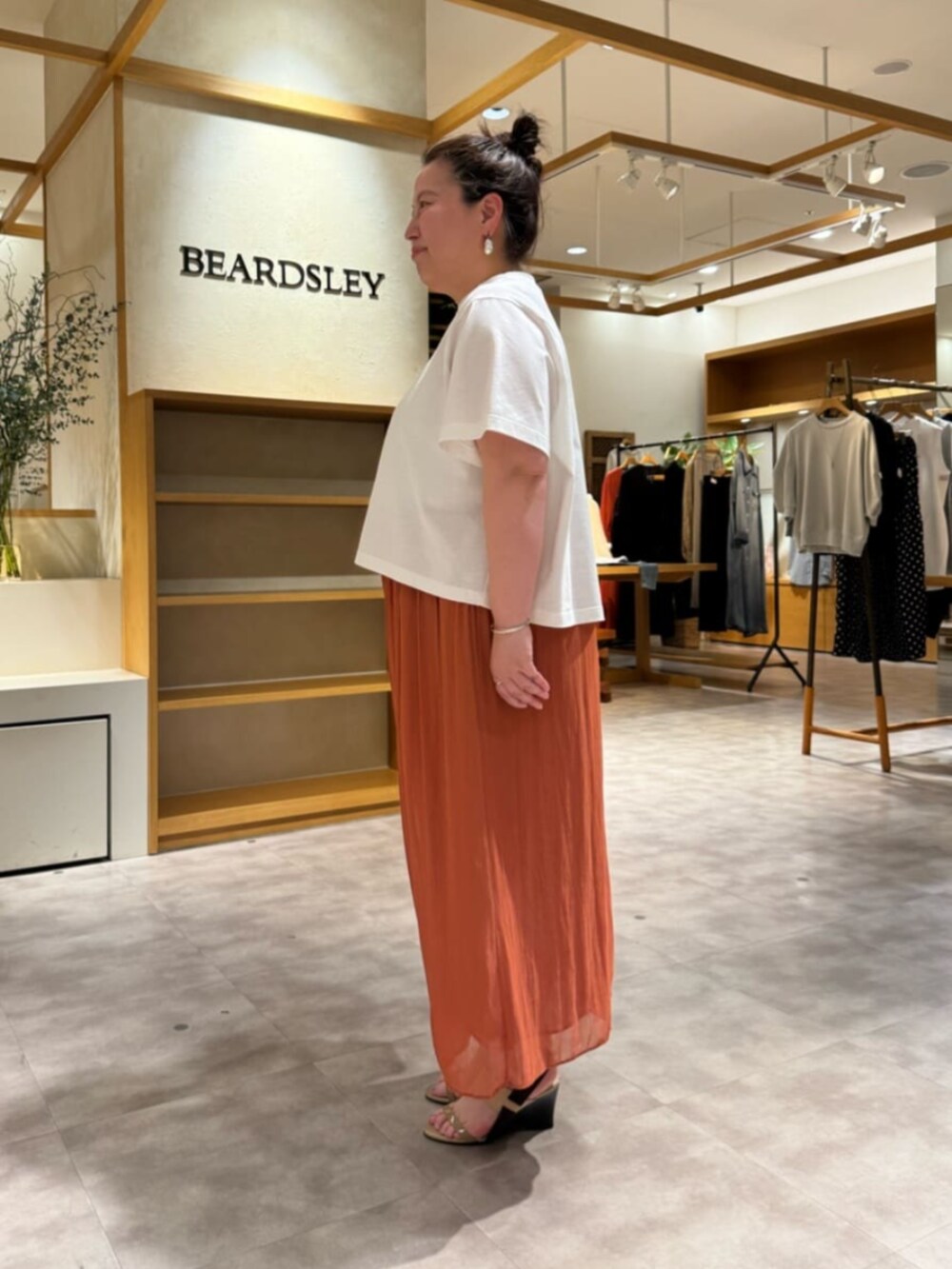ホワイト系のトートバッグ、オレンジ系のその他パンツ、ホワイト系のTシャツ/カットソーを着用したレディースの春コーディネートの4枚目の写真