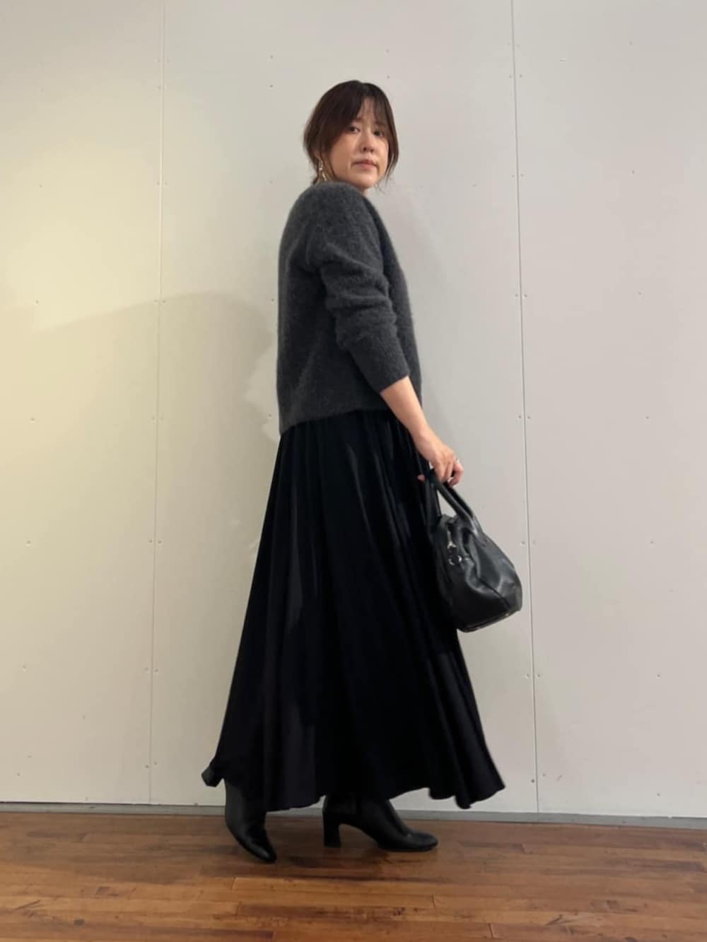 ブラック系のスカート、グレー系のニット/セーターを着用したレディースの秋コーディネートの5枚目の写真