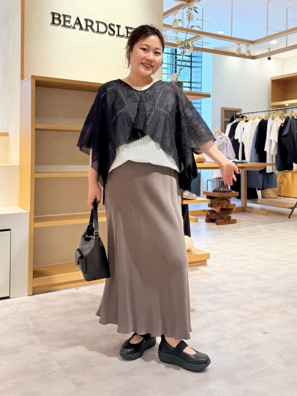 グリーン系のスカート、ブラック系のシャツ/ブラウス、ブラック系のスニーカーを着用したレディースの春コーディネートの3枚目の写真