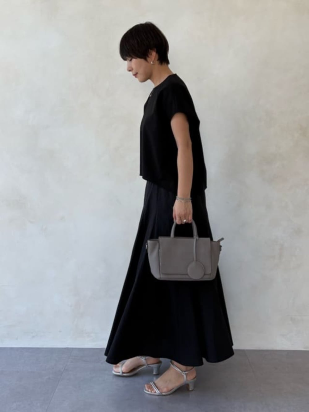グレー系のハンドバッグ、ブラック系のシャツ/ブラウス、ブラック系のスカートを着用したレディースの春コーディネートの2枚目の写真